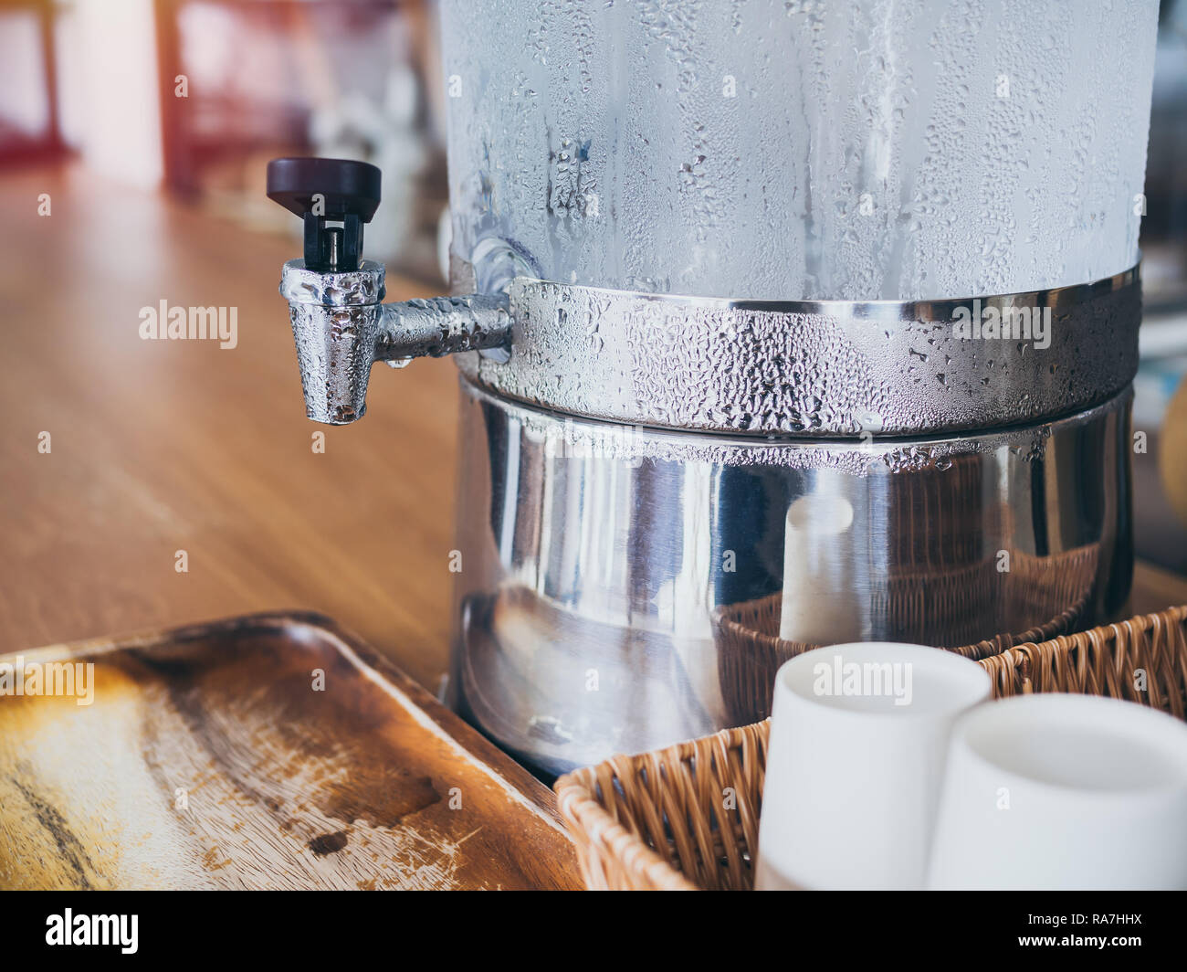 Close-up robinet avec goutte d'eau sur l'eau potable froide glacière avec  tasse de papier sur le tissu sur le plateau de table en bois de service  client dans un café Photo Stock -