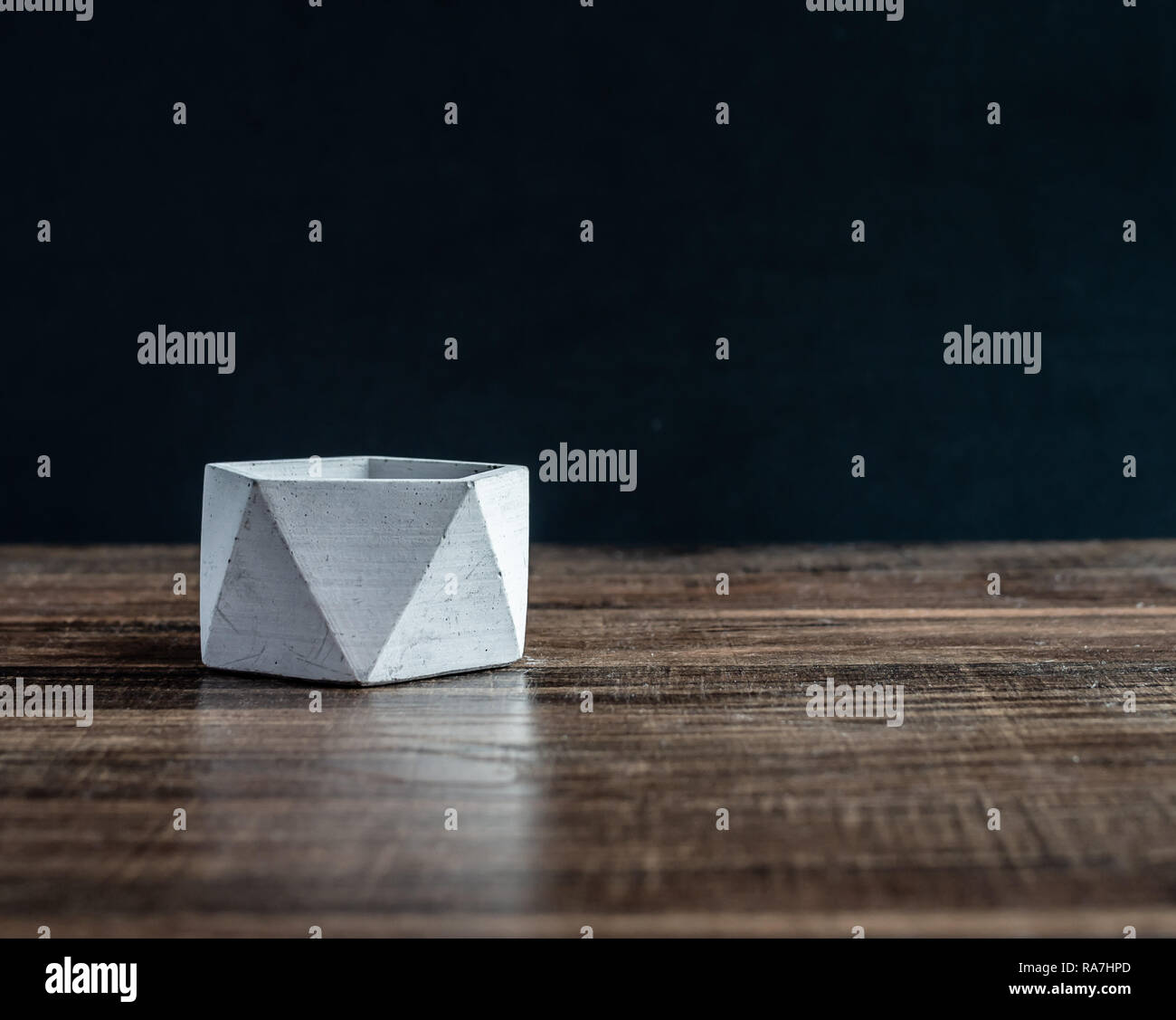 Béton hexagonal moderne vide le semoir sur table en bois isolé sur fond noir avec l'exemplaire de l'espace. Banque D'Images