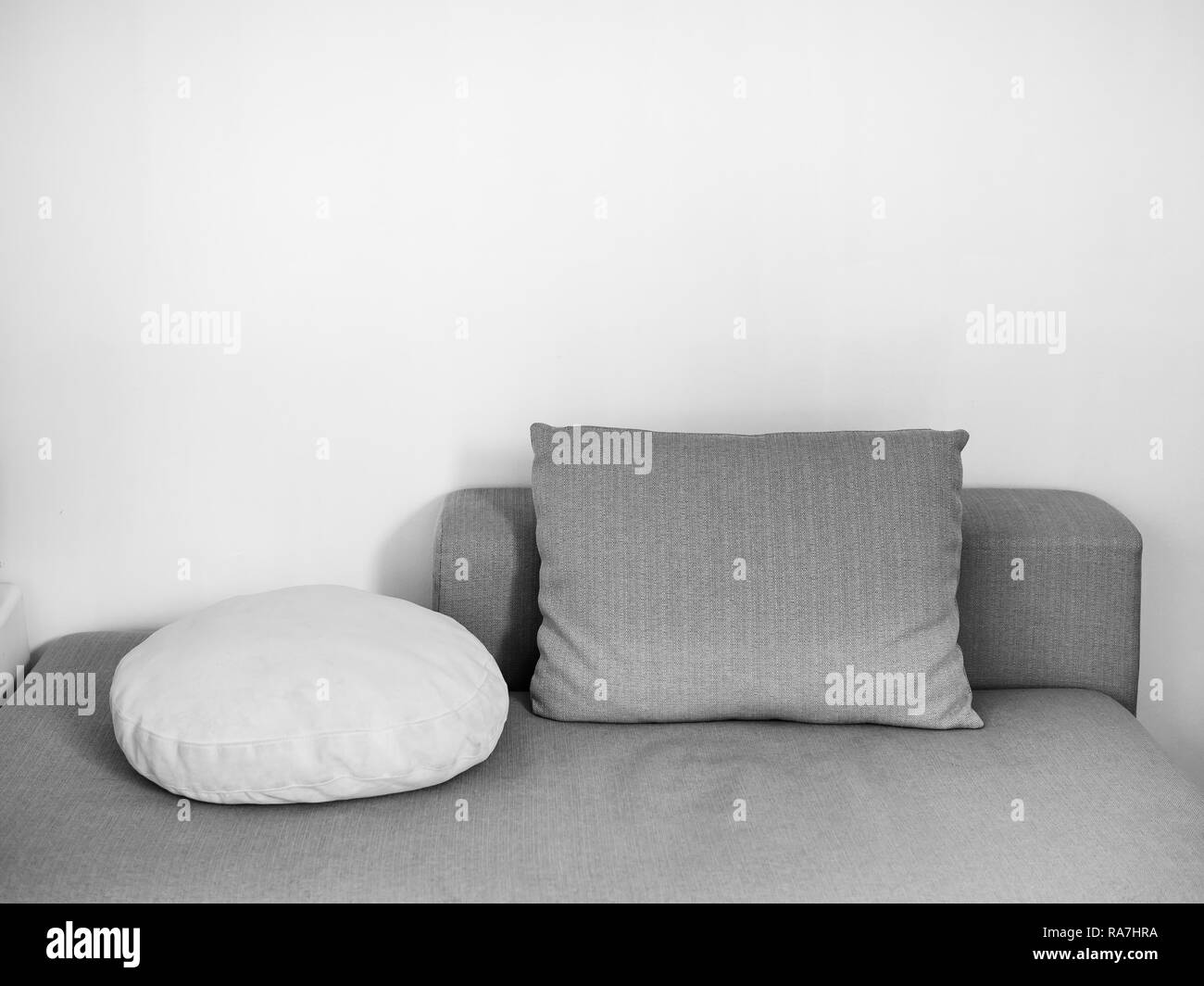Oreillers blanc et gris sur canapé sur mur blanc en arrière-plan de séjour confortable avec copie espace. Banque D'Images