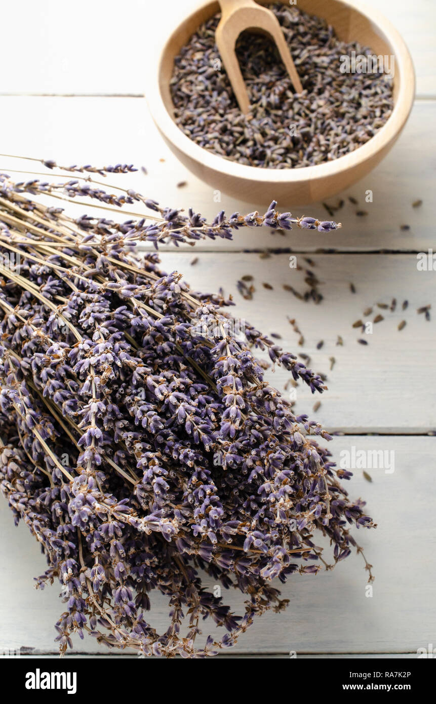 Bouquet de lavande séchées herbes reposant sur des planches de bois peintes en blanc, table avec bol de boutons de fleurs et woden écope en arrière-plan flou.. Banque D'Images