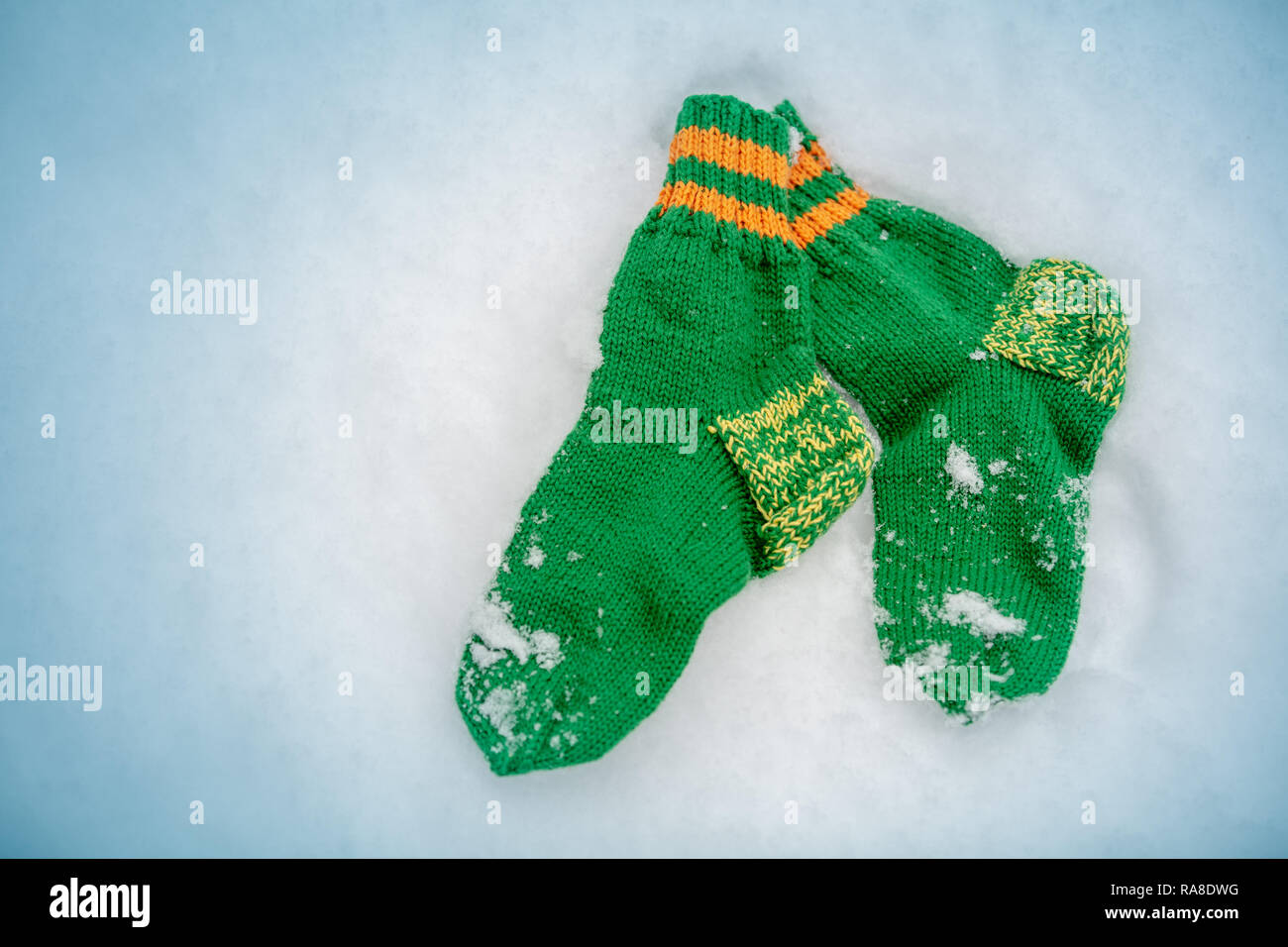 Chaussettes tricotées vert couché sur la neige en hiver Banque D'Images