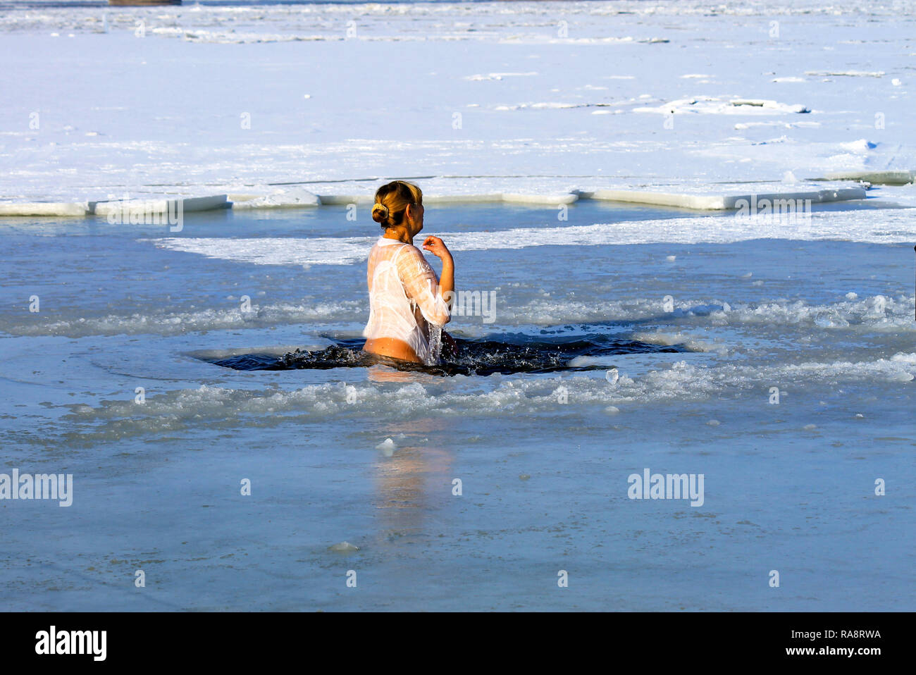 Sport d'hiver. Une femme nage dans la rivière d'hiver couvert de glace pendant les vacances de l'Epiphanie. Le durcissement Banque D'Images