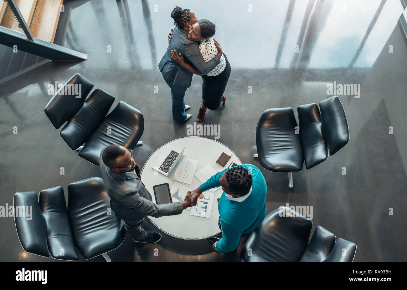 Des collègues africains et message d'abord remercier chacun d'autres après le succès de la réunion. Deux femme sont hugging et deux hommes sont shaking hands Banque D'Images