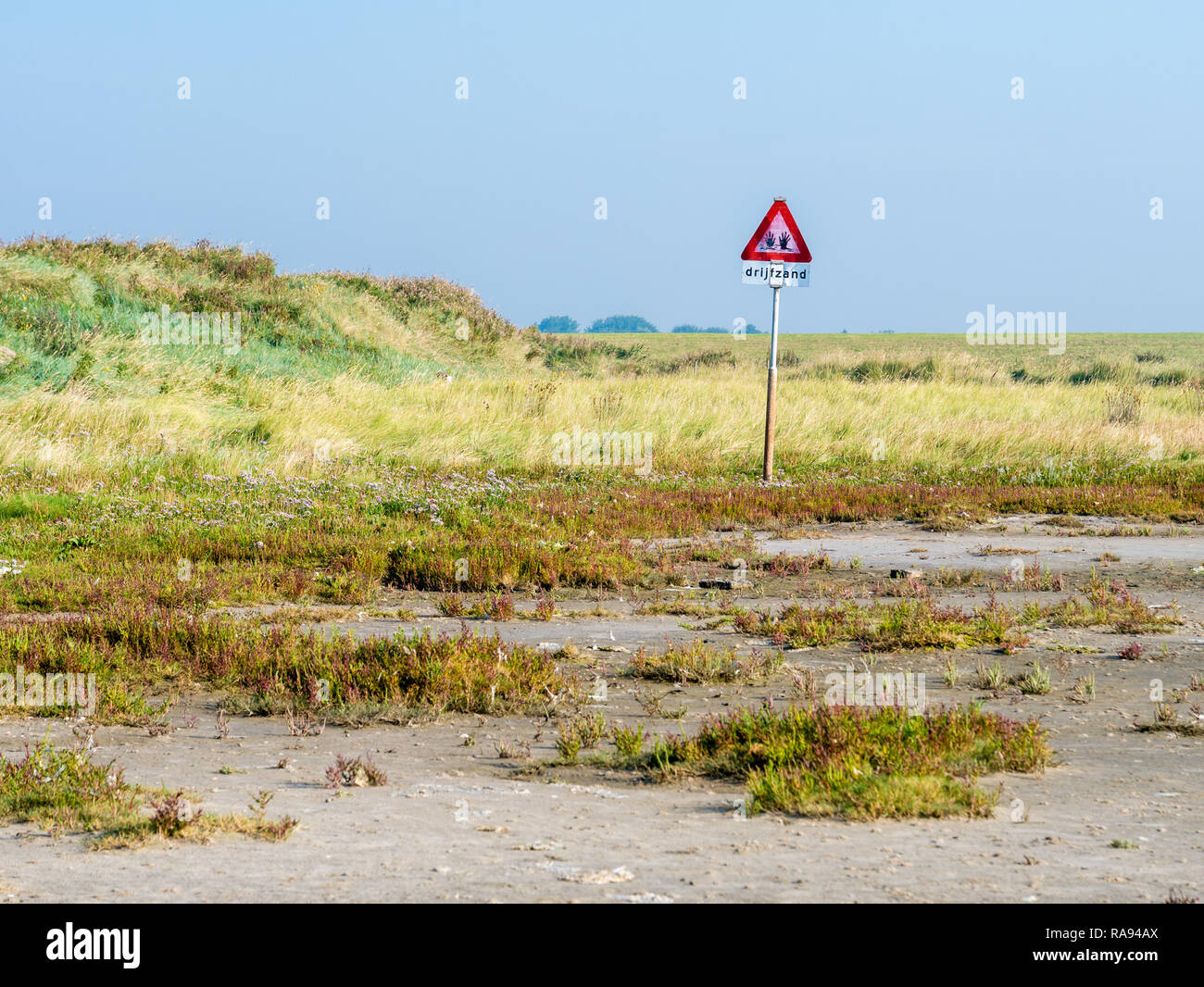 Panneau d'avertissement pour les sables mouvants dangereux dans les marais salés de la côte ouest de l'île de Schiermonnikoog frisonne à marée basse de la mer des Wadden, Pays-Bas Banque D'Images