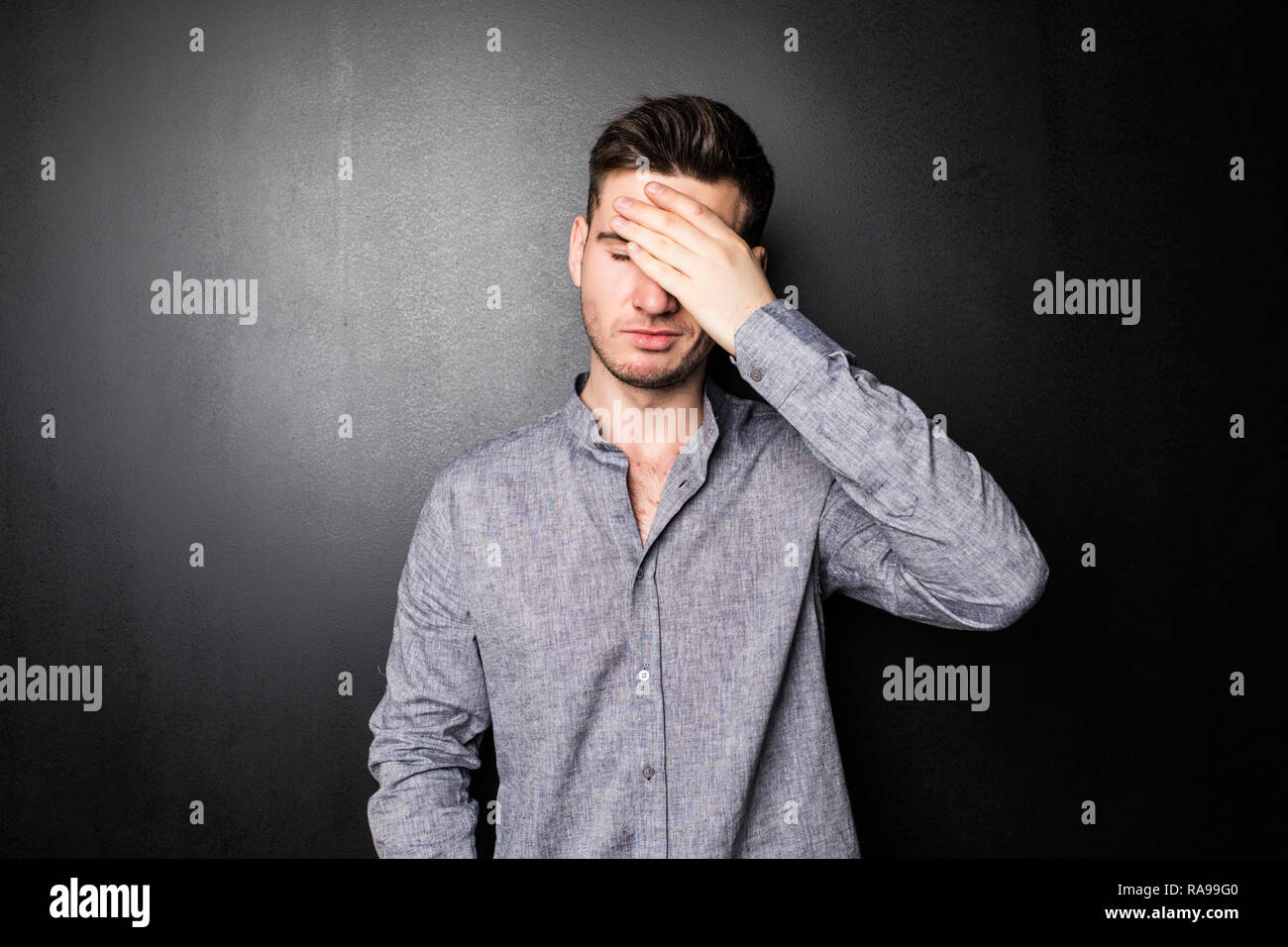 Bel homme se cache le visage avec ses mains, isolé sur fond noir Photo  Stock - Alamy