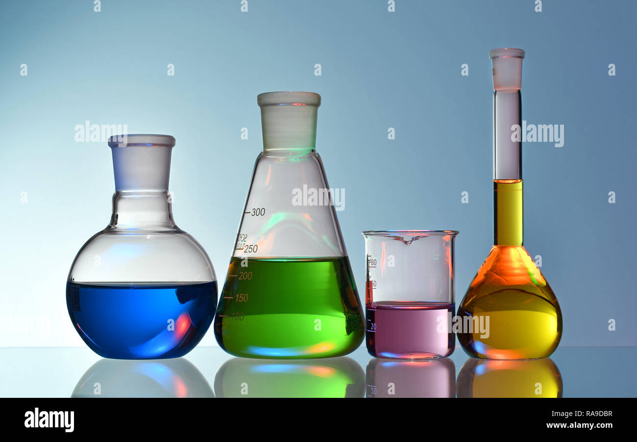 Verrerie de laboratoire avec des produits chimiques et des liquides colorés sur fond bleu Banque D'Images
