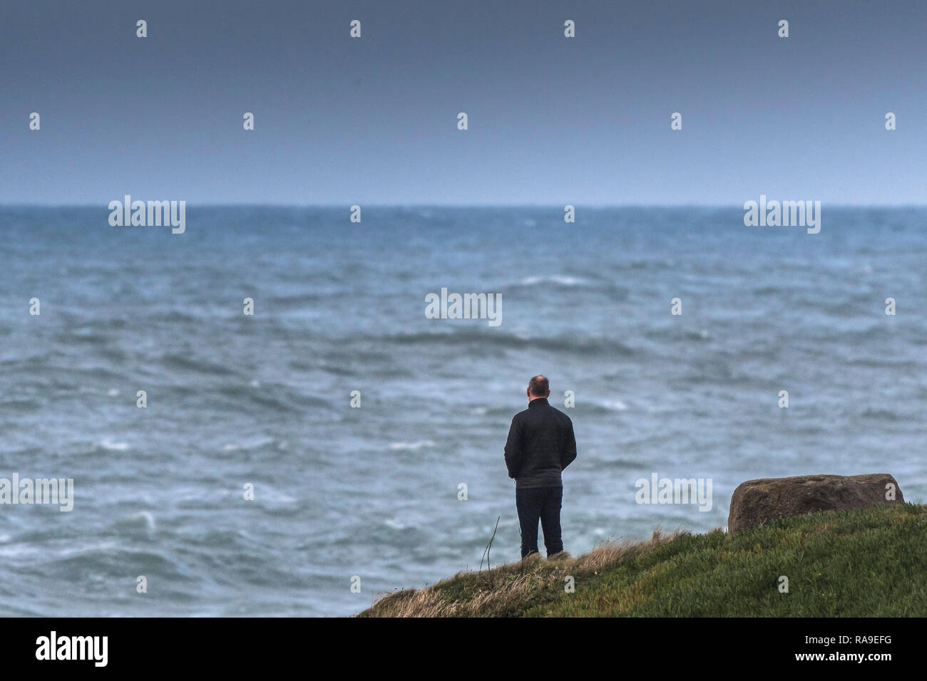 Un homme debout sur un promontoire face à la mer. Banque D'Images