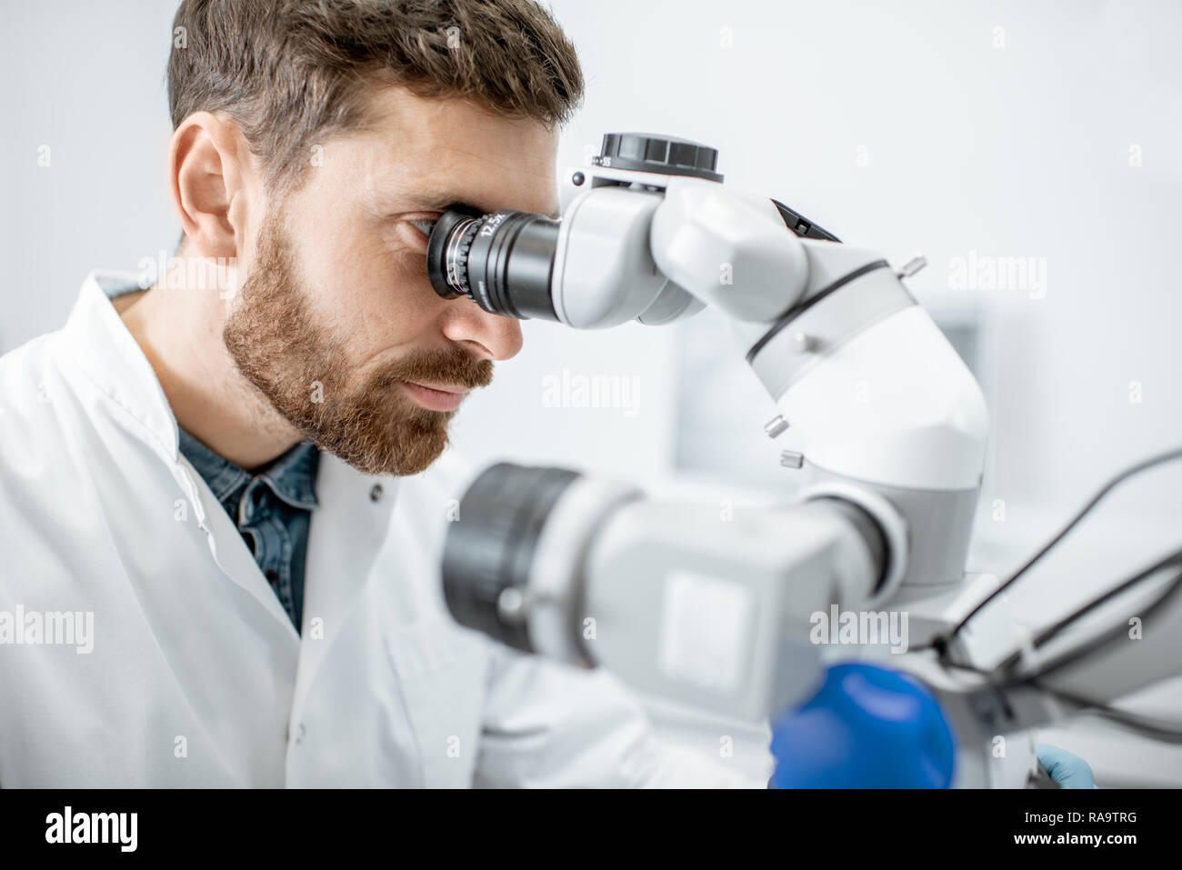 Male dentist examining patient avec un microscope professionnel au cabinet dentaire Banque D'Images