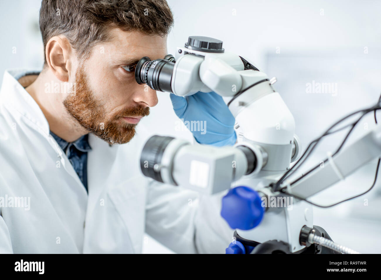 Male dentist examining patient avec un microscope professionnel au cabinet dentaire Banque D'Images