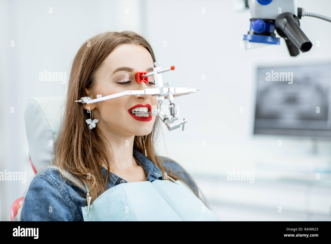 Jeune femme avec système de mesure de la mâchoire du patient sur son visage assis dans le cabinet dentaire Banque D'Images