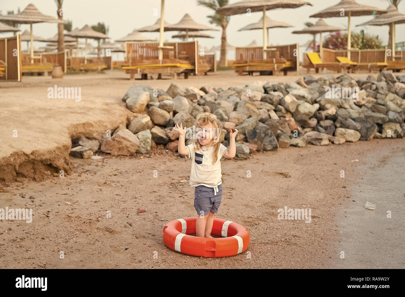 Petit Garcon De Bebe Ou Enfant Mignon Visage Heureux Et Avec Des Cheveux Blonds En Shirt Short Et Pieds Nus Jouant Avec La Ceinture Rouge Ou Bouee A Plage De Sable Avec Petit Garcon De Bebe Ou Enfant Mignon Visage Heureux Et Avec Des Cheveux Blonds En Shirt Short Et Pieds Nus Jouant Avec La Ceinture Rouge Ou Bouee A Plage De Sable Avec