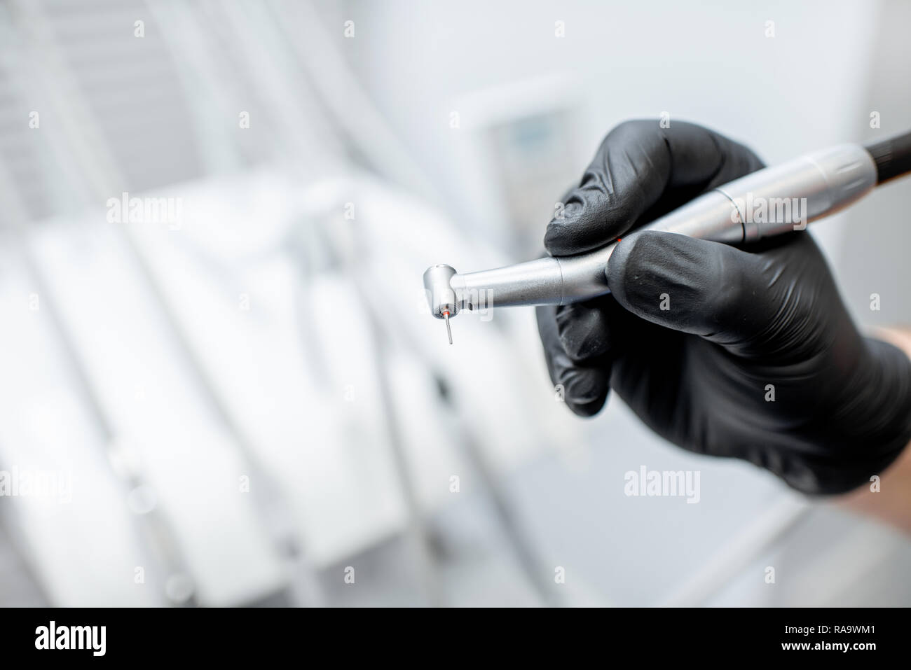 Close-up d'une fraise dentaire avec l'injecteur dans les mains en noir gants médicaux Banque D'Images