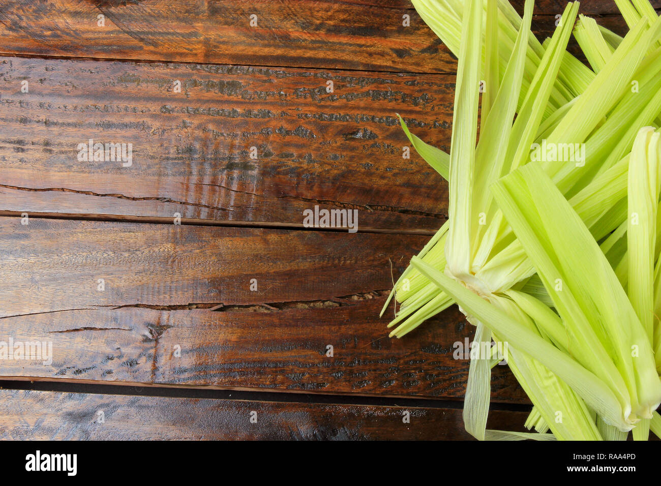 L'écorce et de la paille de maïs vert, récoltés à partir de la plantation, sur table en bois rustique, de l'espace pour le texte. Banque D'Images