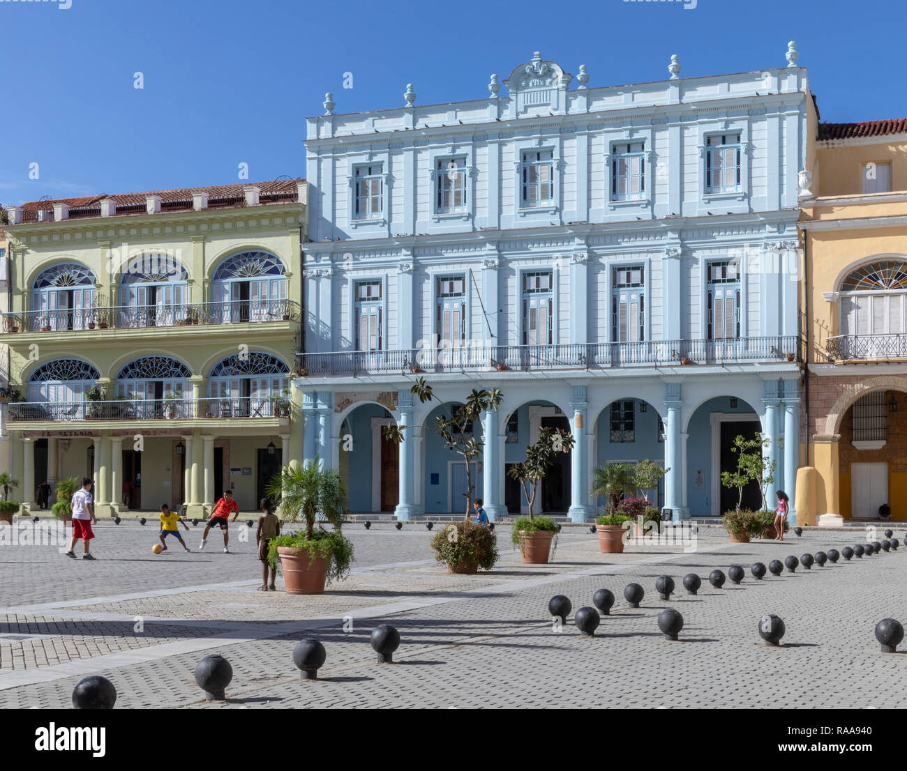 Stuc peint des bâtiments de l'époque coloniale et les garçons jouent au football, la Plaza Vieja, La Havane, Cuba Banque D'Images