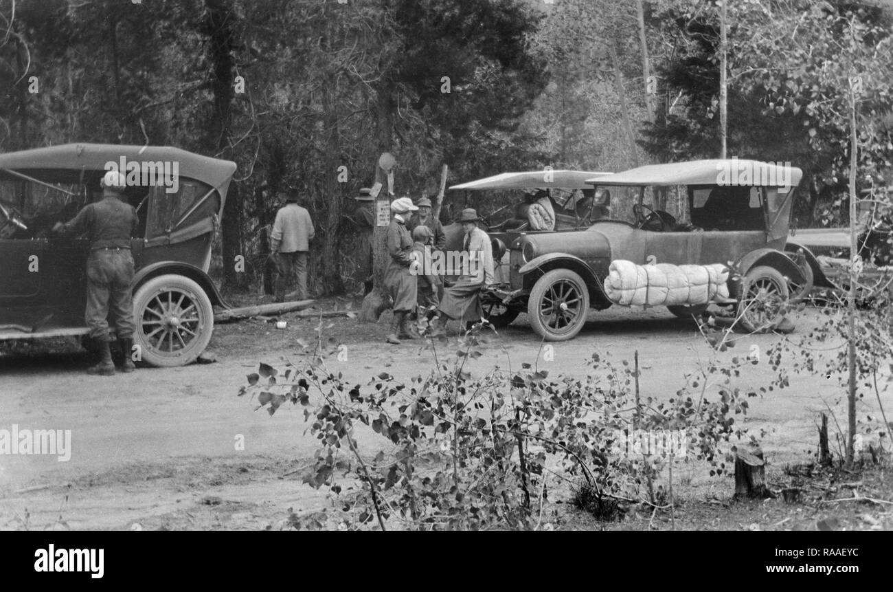 Un groupe de jeunes adultes pack jusqu'les voitures après un voyage de camping, ca. 1928. Banque D'Images