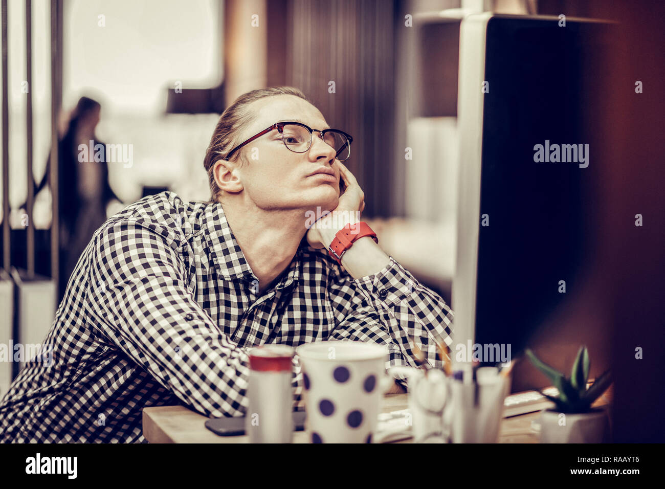 Bored young man leaning on sa table Banque D'Images