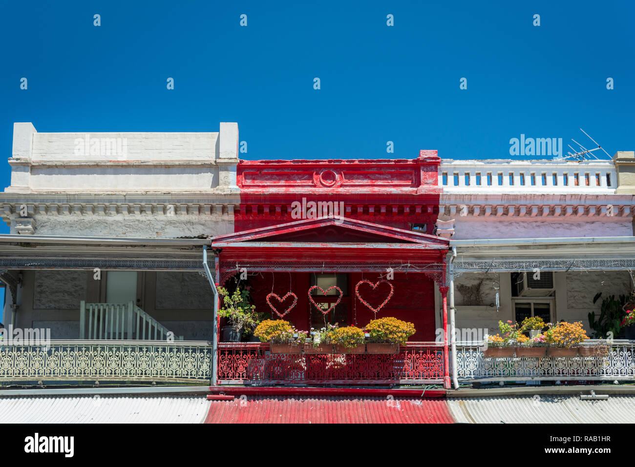 Une maison peinte en rouge et l'affichage de l'amour des Coeurs, se détachant sur les autres maisons peintes en blanc contre un ciel bleu Banque D'Images