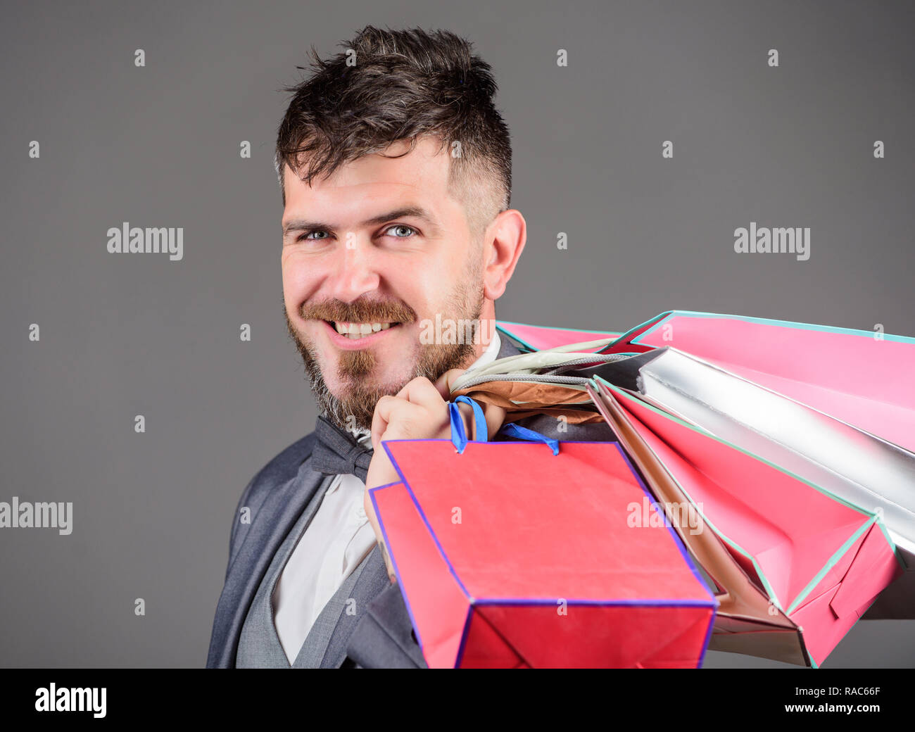 L'homme d'affaires élégant barbu transporter les sacs sur fond gris. Faire des achats plus joyeux. Boutique d'élite. Profitez des boutiques des affaires. C'est le black friday. Shopping avec un rabais profitez de l'achat. Banque D'Images