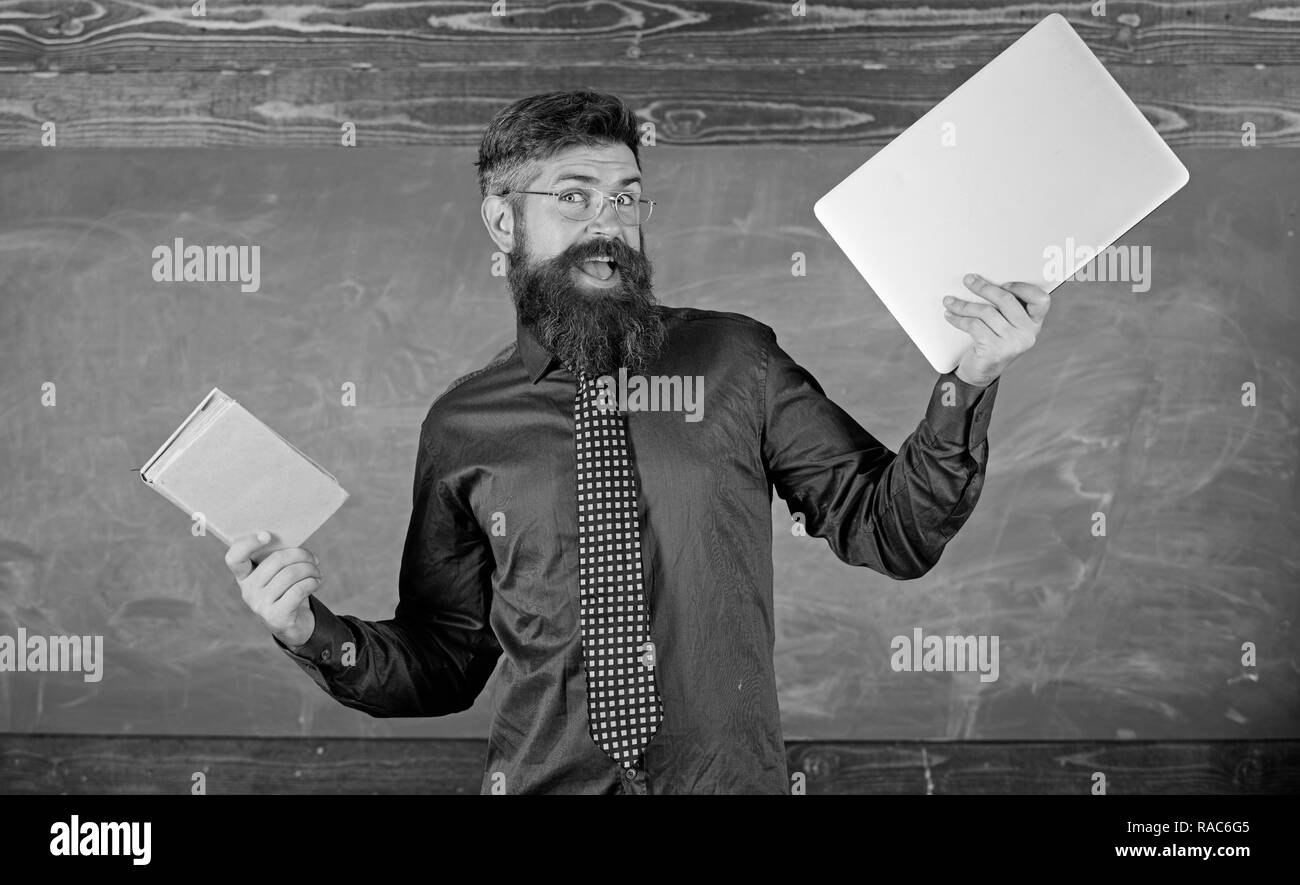 Hipster barbu de l'enseignant est titulaire d'adresses et ordinateur portable. Qu'est-ce que vous le souhaitez. Le choix d'enseignants de l'enseignement moderne approche. Livre papier contre l'ordinateur portable. Papier contre numérique. Choisissez la méthode d'enseignement droit. Banque D'Images