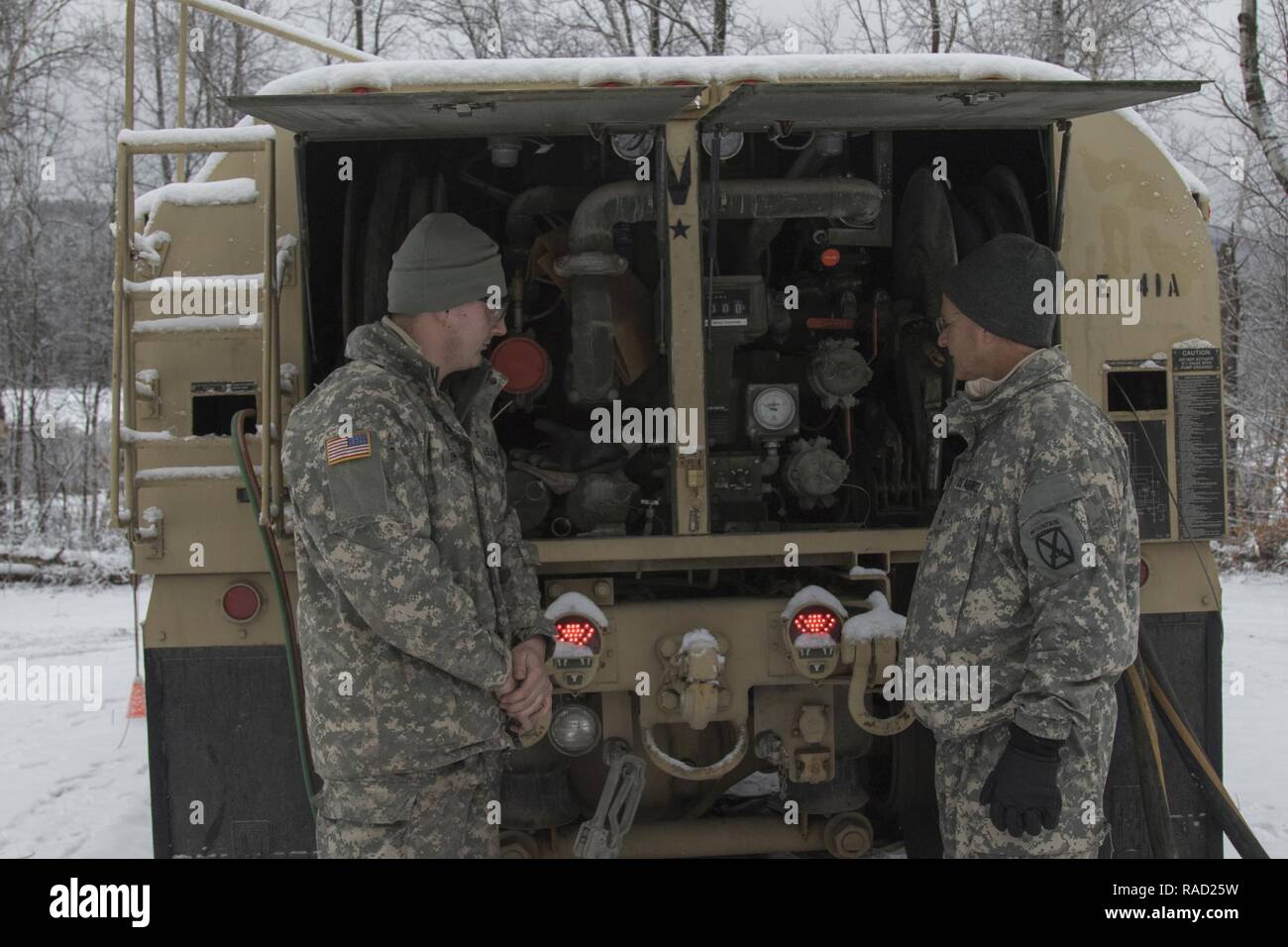 Le sergent de l'armée américaine. Devin Johnson, à gauche, un fueler avec la Compagnie Golf du 186ème Bataillon de soutien de la Brigade de la Garde nationale, Vermont, explique les différentes parties d'un camion de carburant à l'Air Force, le général Steven Cray, droit, adjudant général, au Camp d'Ethan Allen Site de formation, Jericho, Vermont, le 25 janvier 2017. Cray a visité les soldats pendant leur formation annuelle d'hiver. Banque D'Images