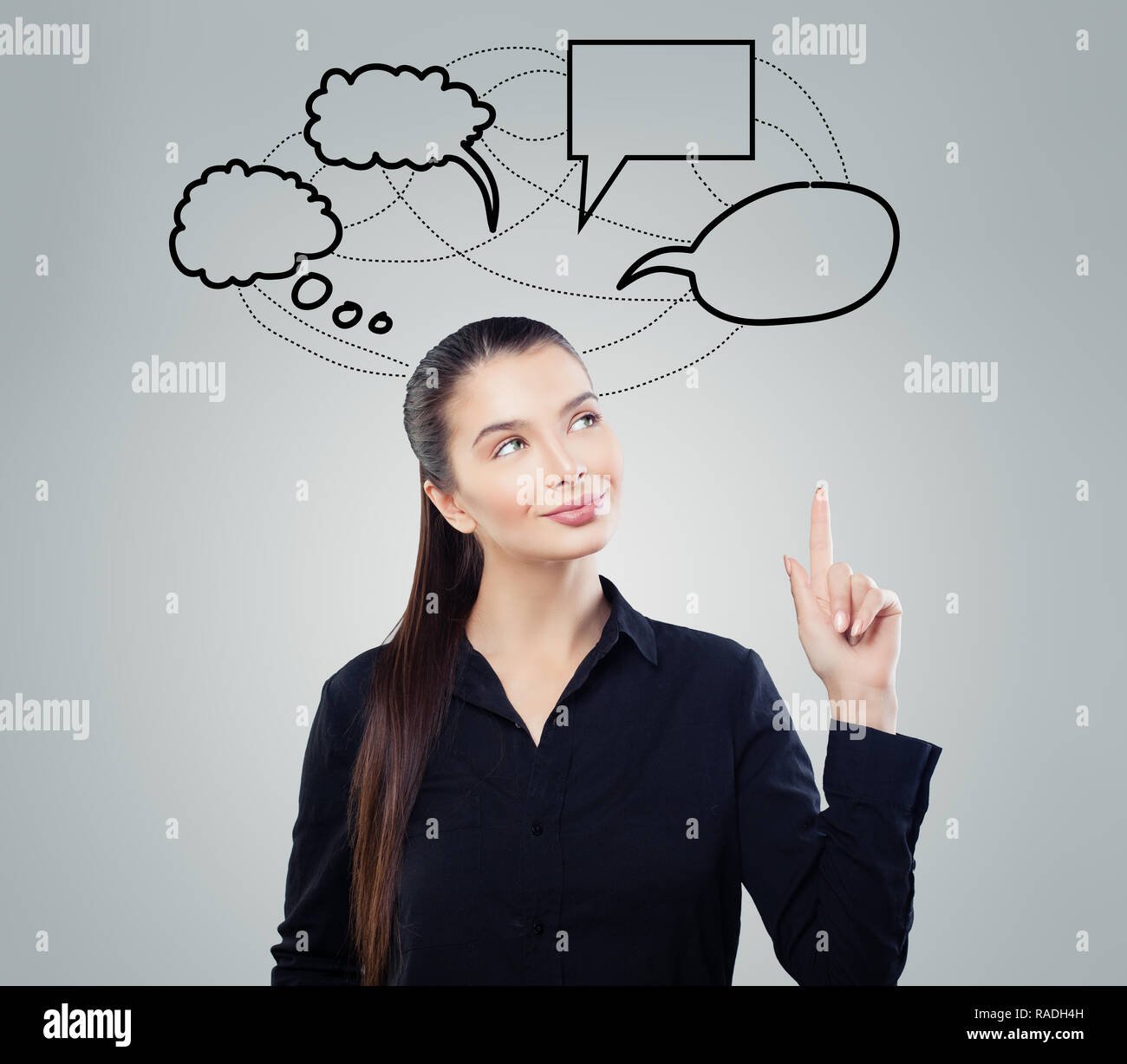 Smiling business woman pointing sur bulle vide nuages sur fond gris Banque D'Images