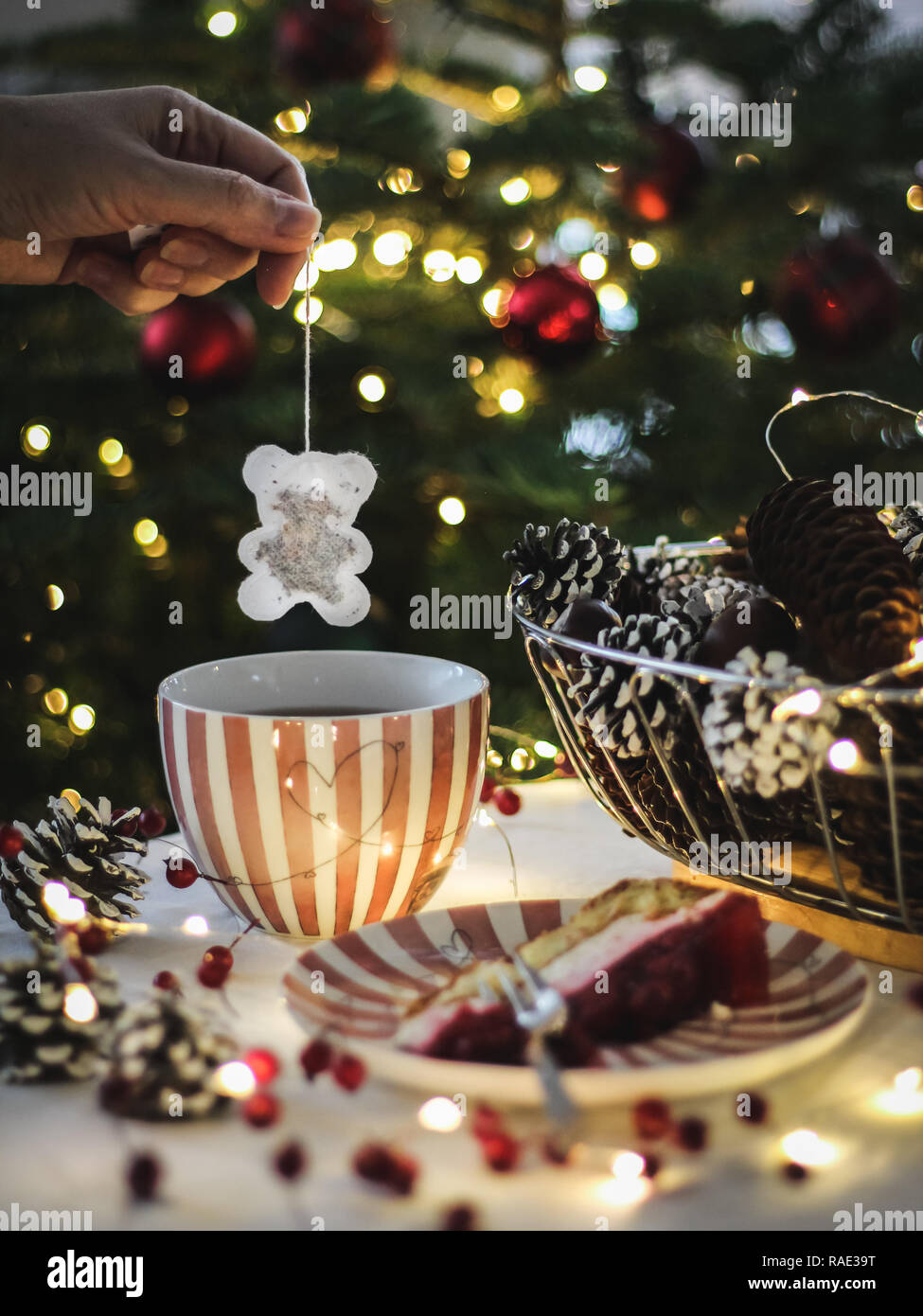 Boire le thé avec un gâteau à côté de l'arbre de Noël Banque D'Images