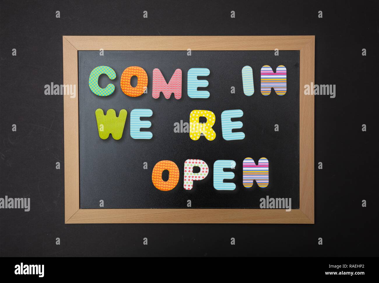 Ouvrir, entrez. Carte avec cadre noir, texte, nous ouvrir de nouveau en lettres colorées, noir wall background Banque D'Images