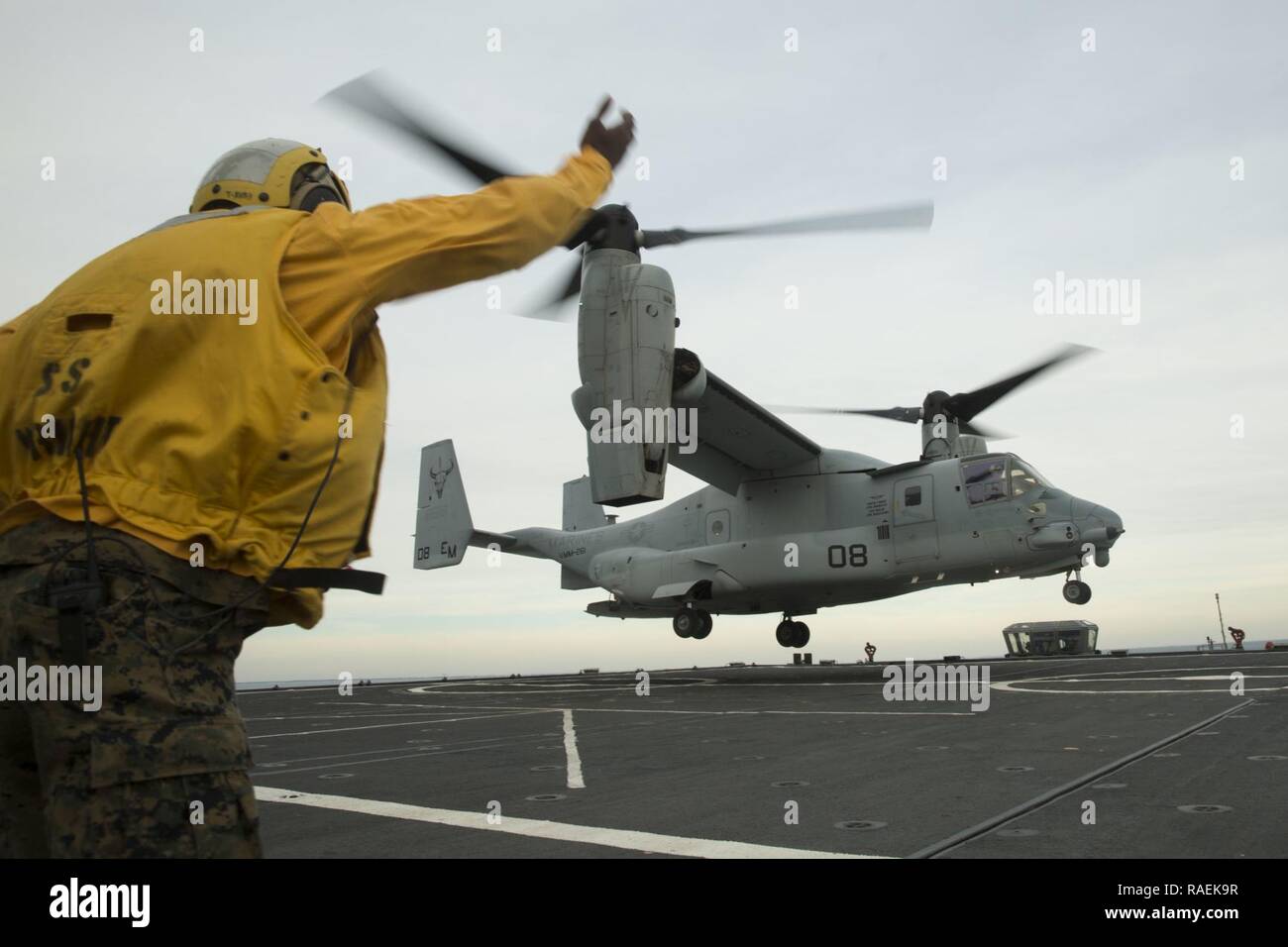 Le sergent des Marines des États-Unis. Reginald Johnson, un spécialiste de l'assistance d'atterrissage avec Marine Aviation Escadron logistique 29, signe d'un MV-22 Osprey de s'écarter de l'Wright-class aviation soutenir container ship SS Wright au cours du navire à la terre exerce sur la côte de Camp Lejeune, en Caroline du Nord, le 12 décembre 2018. L'escadron 261 à rotors basculants moyen Marine Incorporated un MV-22 conjointement avec un T-AVB pour la première fois au cours d'exercices du navire à la terre. Banque D'Images