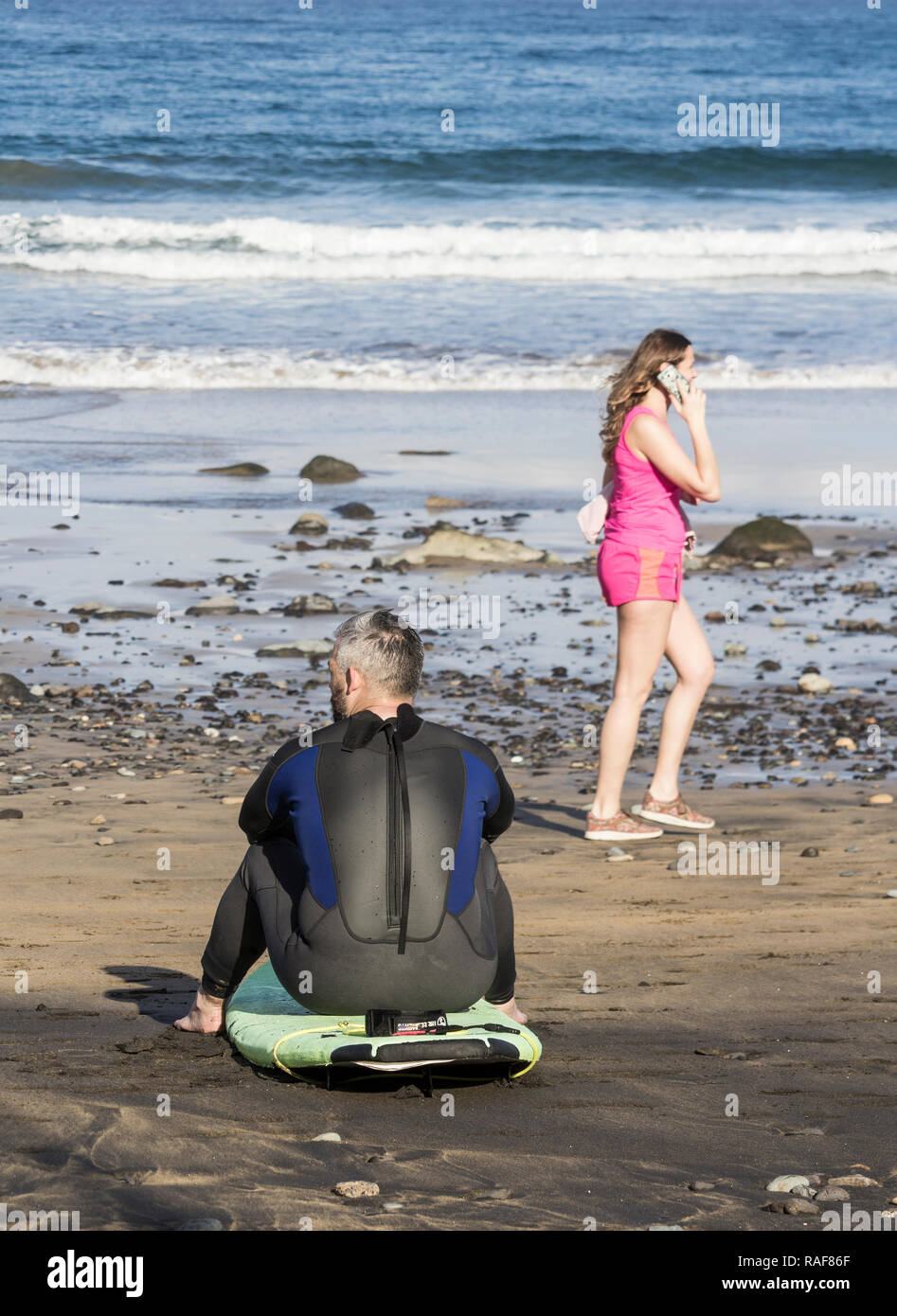 Surf mature sitting on surfboard on beach. Banque D'Images