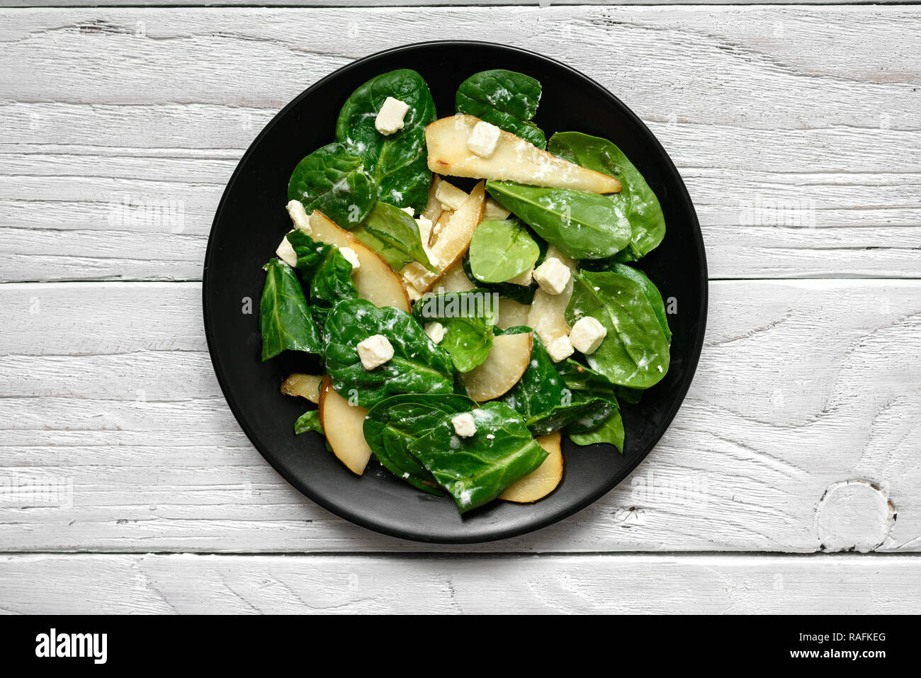 Salade avec les feuilles d'épinards, poire et fromage feta en plaque noire. La nourriture végétarienne saine. Vue de dessus Banque D'Images