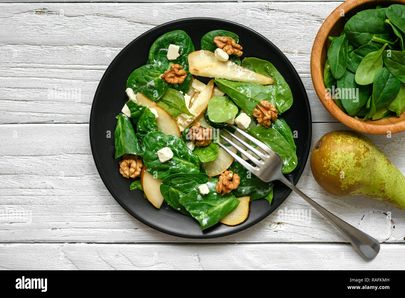 Salade vitamine avec les feuilles d'épinards, poire, noix et fromage feta avec fourchette en plaque noire. La nourriture végétarienne saine. Vue de dessus Banque D'Images