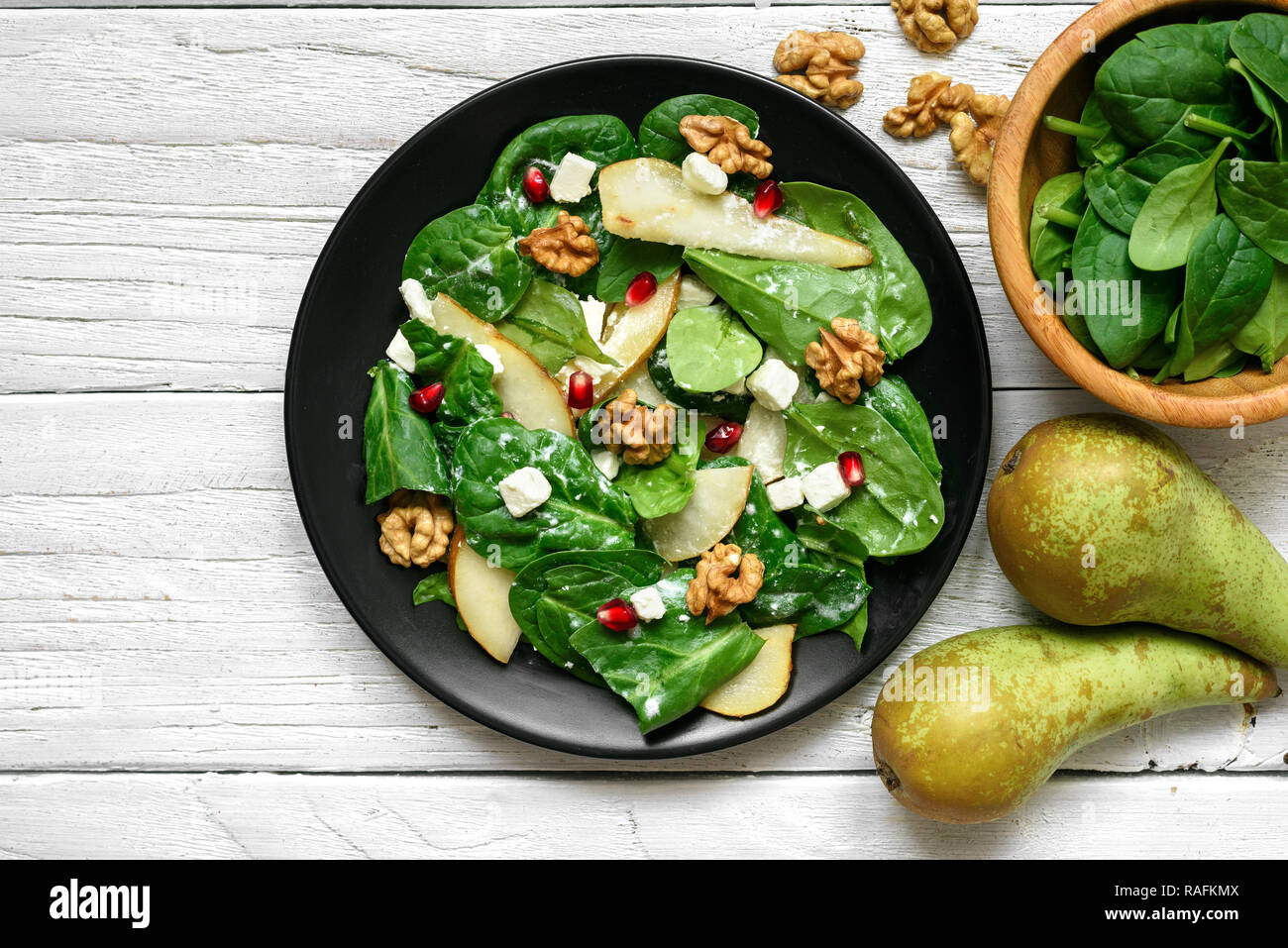 Salade vitamine avec les feuilles d'épinards, de poire, de noix, de grenade et le fromage feta en plaque noire. La nourriture végétarienne saine. Vue de dessus Banque D'Images
