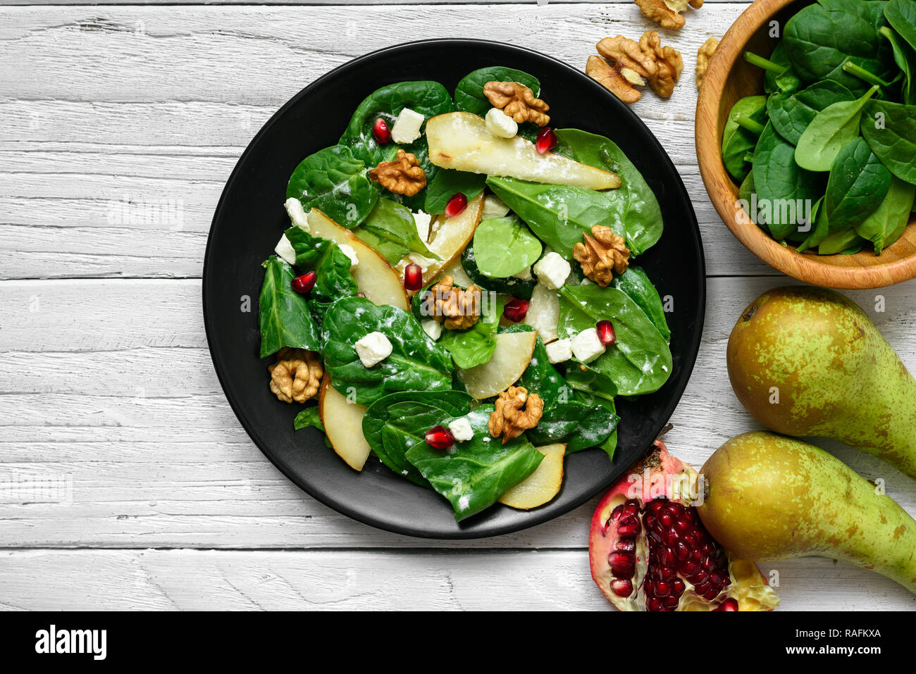 Salade de printemps frais avec les feuilles d'épinards, de poire, de noix, de grenade et le fromage feta en plaque noire. La nourriture végétarienne saine. Vue de dessus Banque D'Images