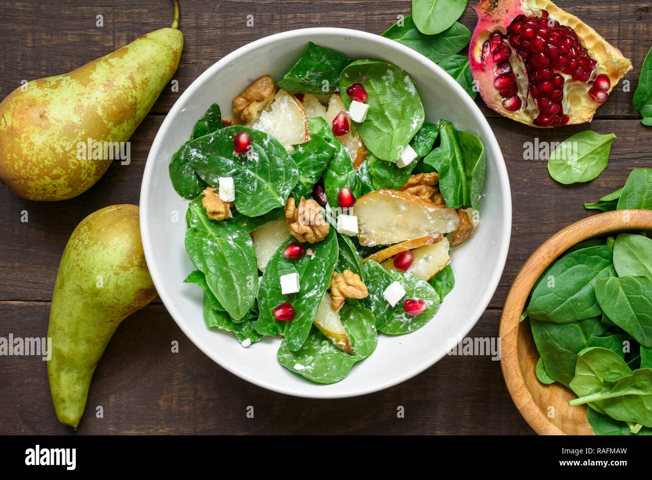 Salade avec les feuilles d'épinards, de poire, de noix, de grenade et de la feta dans un bol alimentaire végétarien sain. Vue de dessus. Banque D'Images