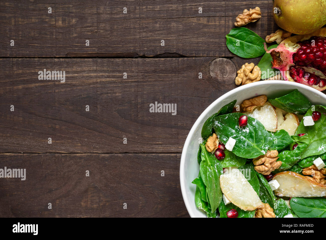 Salade avec les feuilles d'épinards, de poire, de noix, de grenade et de la feta dans un bol alimentaire végétarien sain.. Vue de dessus with copy space Banque D'Images