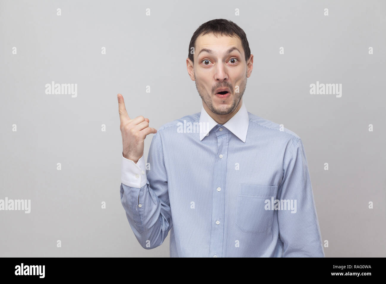 J'ai une idée. Portrait of happy surpris handsome businessman in bristle classique bleu shirt debout avec doigt vers le haut et à la caméra à l'intérieur. s Banque D'Images