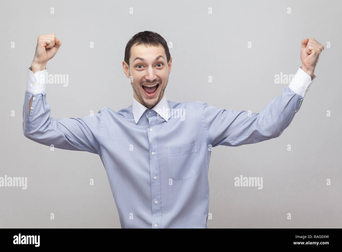 Portrait d'homme en soie beau joyeux excité dans classic light blue shirt debout avec les bras levés et de célébrer sa victoire. Piscine stud Banque D'Images Portrait d'homme en soie beau joyeux excité dans classic light blue shirt debout avec les bras levés et de célébrer sa victoire. Piscine stud Banque D'Images