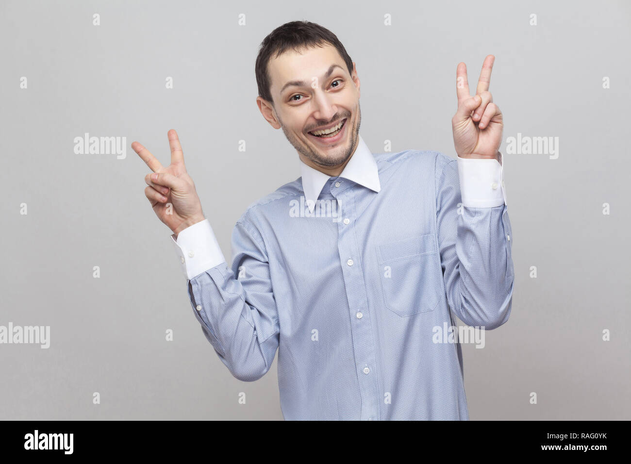 Portrait de funny happy handsome businessman in bristle classic shirt standing looking at camera avec la paix ou la victoire et sourire à pleines dents. Piscine s Banque D'Images Portrait de funny happy handsome businessman in bristle classic shirt standing looking at camera avec la paix ou la victoire et sourire à pleines dents. Piscine s Banque D'Images