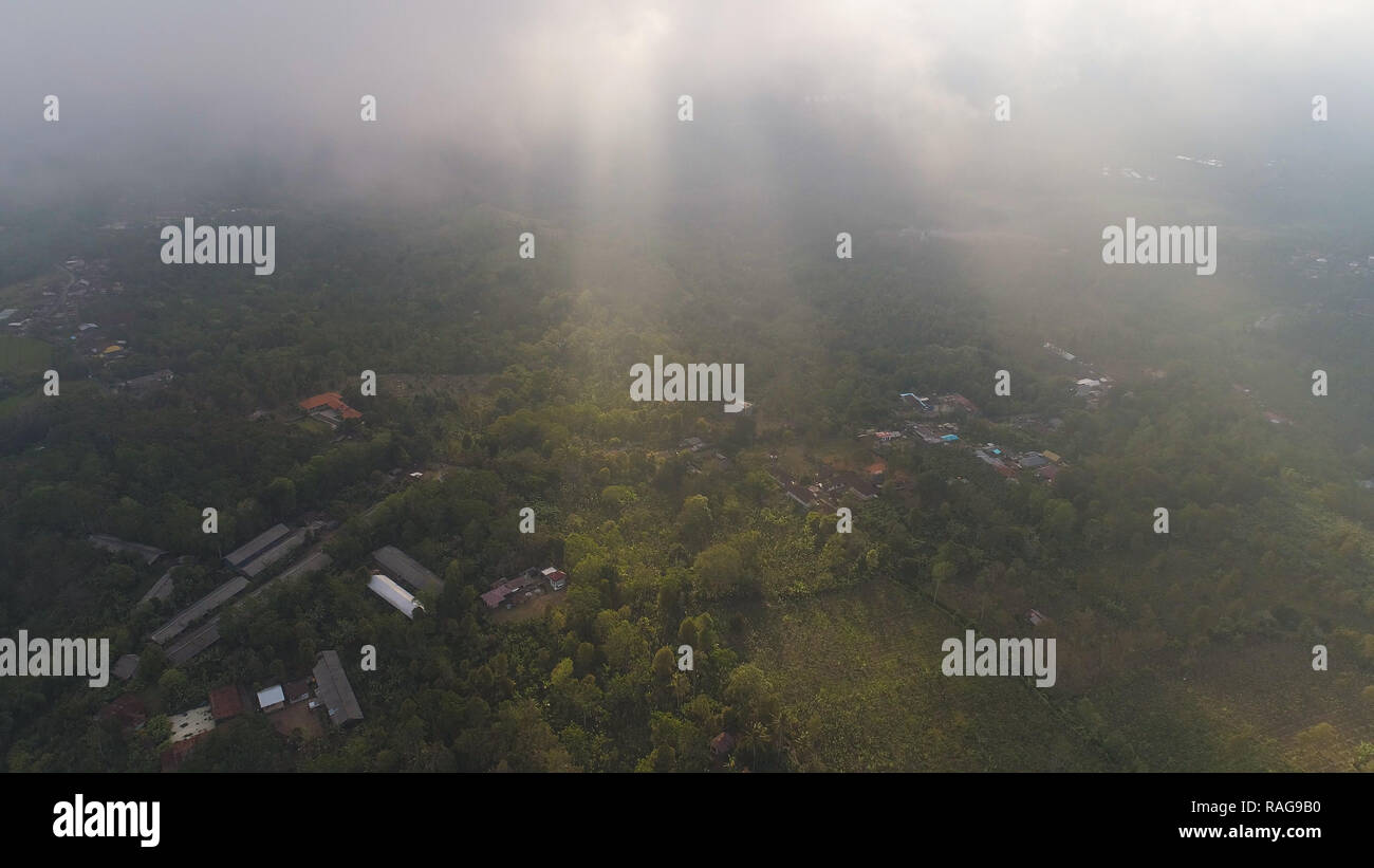 Vue aérienne du village de ferme parmi les terres agricoles avec des nuages au coucher du soleil. Les terres agricoles, les terres couvertes de nuages, champs avec des cultures, des arbres. paysage tropical Bali, Indonésie. Banque D'Images