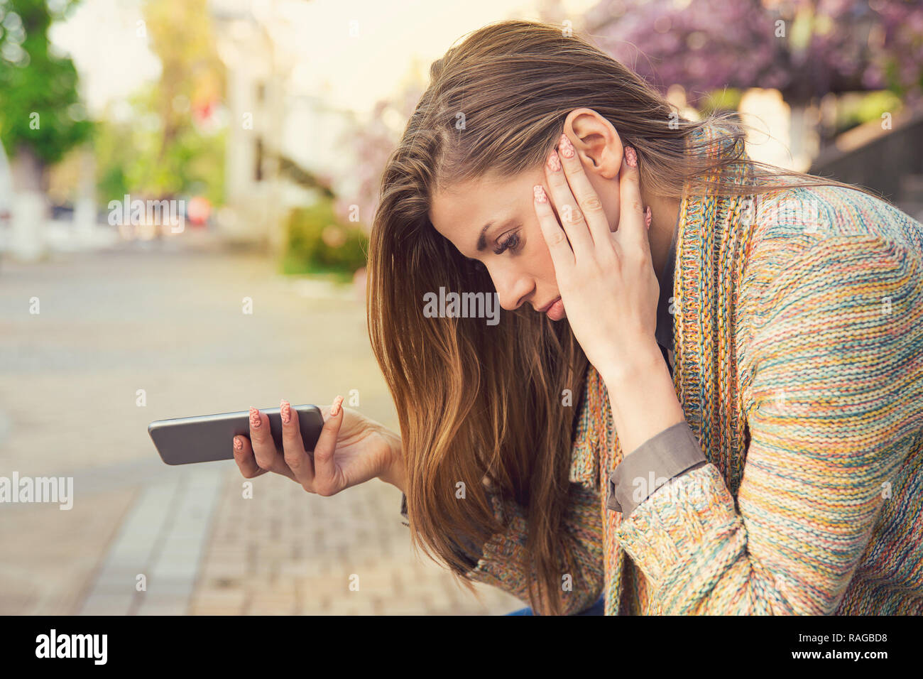 Side view of young woman holding phone et à la rupture avec plaisir tout en étant assis sur la rue Banque D'Images