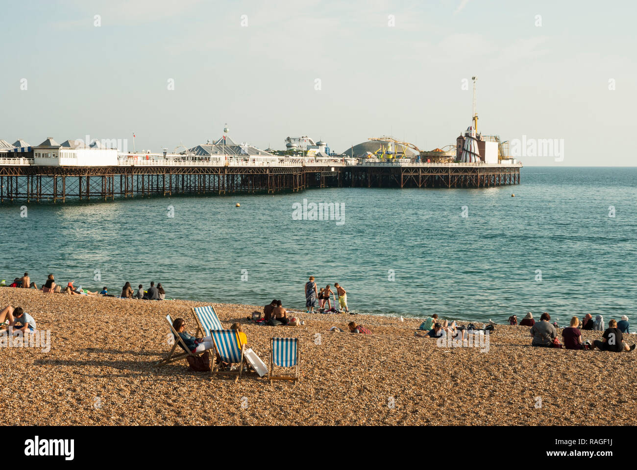 Vue sur la plage de Brighton à la fin de l'été soleil avec les vacanciers détente sur la plage avec chaises longues dans certains palais de Brighton Pier dans l'arrière-plan Banque D'Images