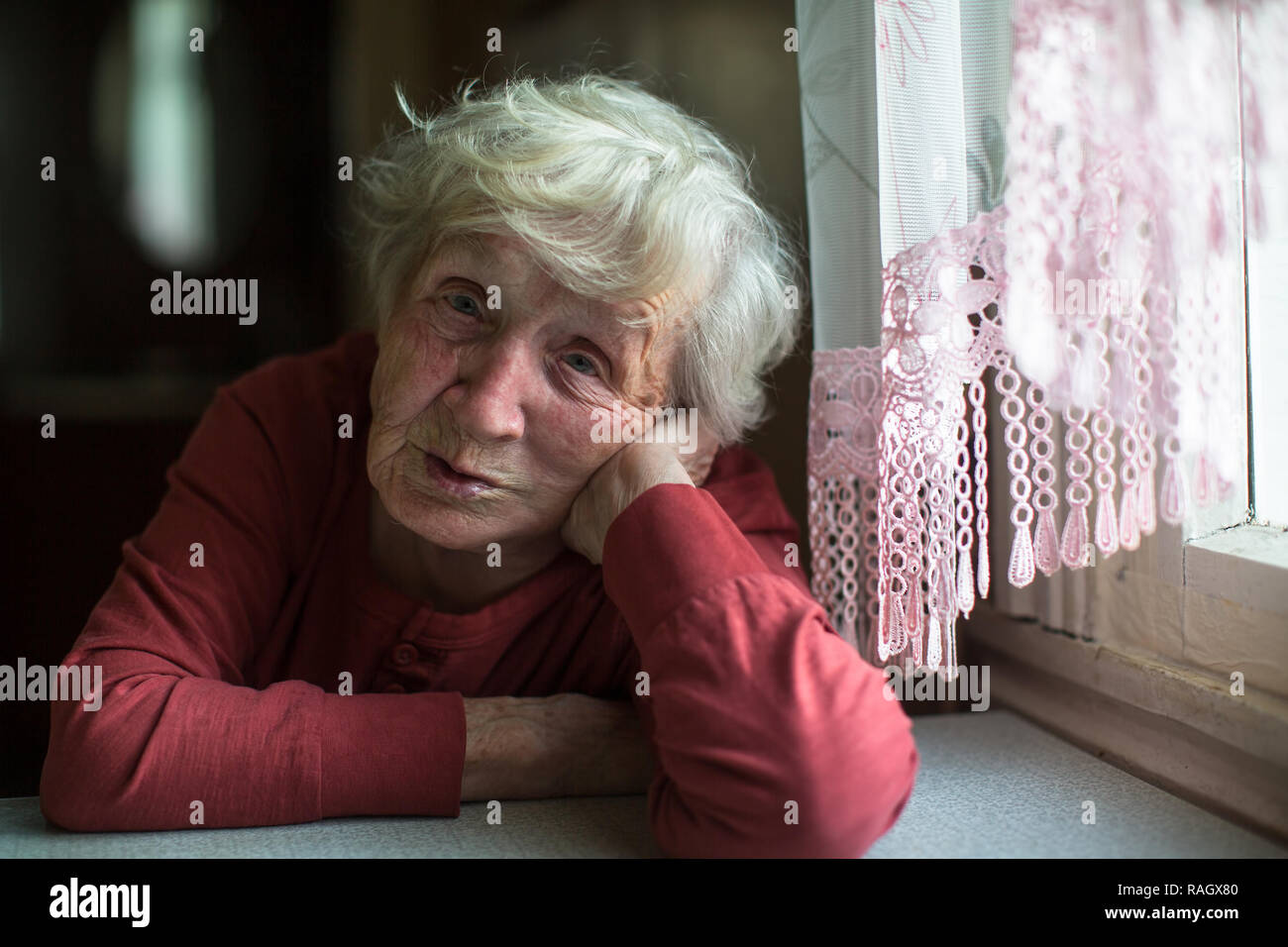Les émotions d'une femme âgée assise à la table. 90 ans. Banque D'Images