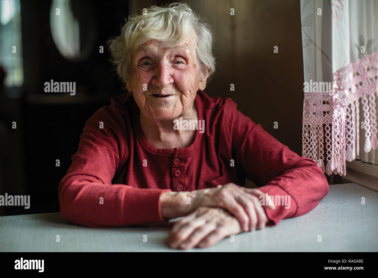 Les émotions d'une femme âgée assise à la table. 90 ans. Banque D'Images