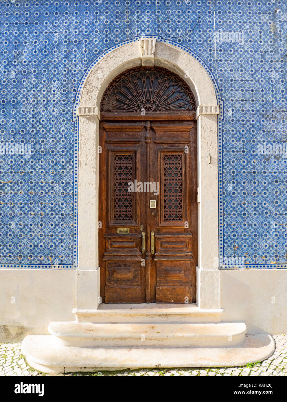 Lisbonne - Portugal, façade d'une maison couverte de tuiles bleues typiques, des azulejos, et ancienne porte en bois décorés Banque D'Images