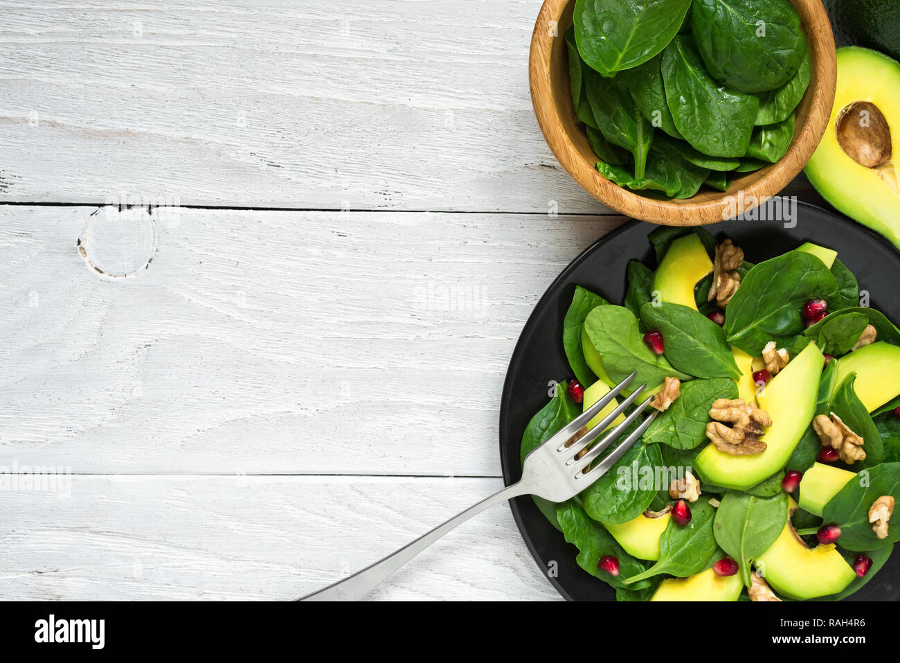 Salade fraîche avec de l'avocat, épinards, grenade et noix dans la plaque noire avec une fourchette. alimentation saine. top view with copy space Banque D'Images