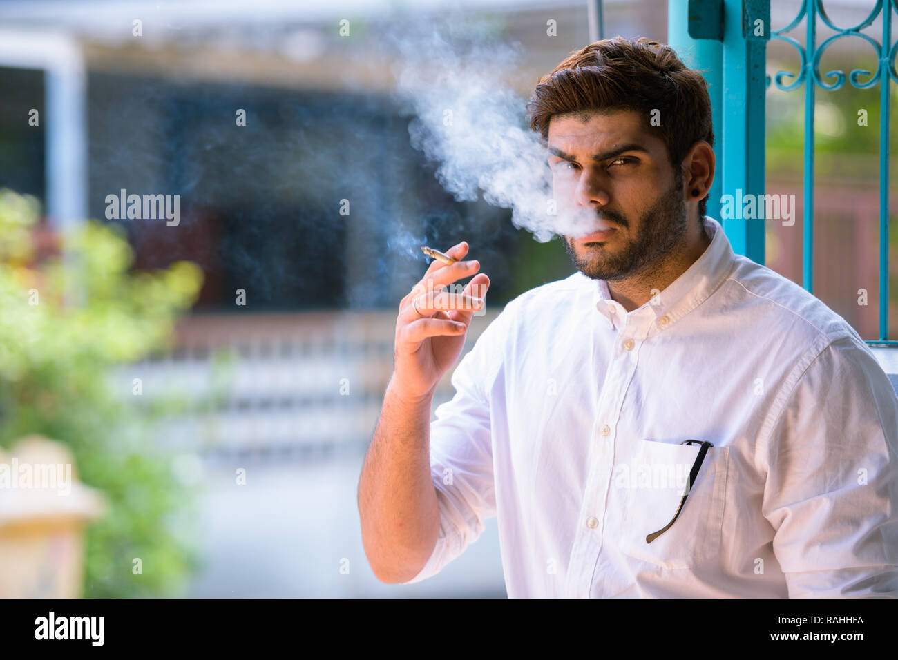 Beau jeune homme indien barbu cigarette à l'extérieur Banque D'Images