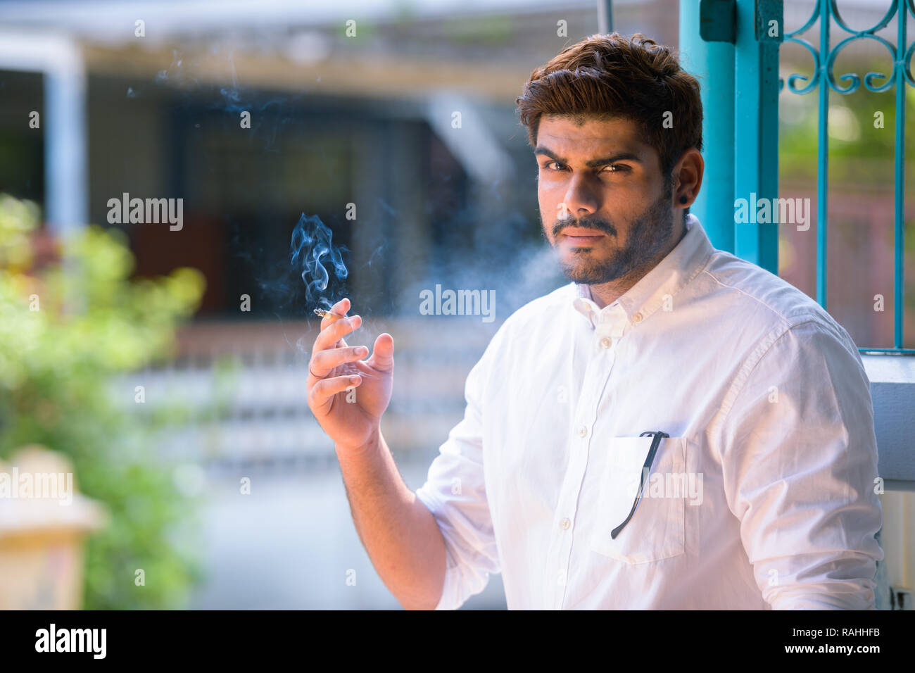 Beau jeune homme indien barbu cigarette à l'extérieur Banque D'Images