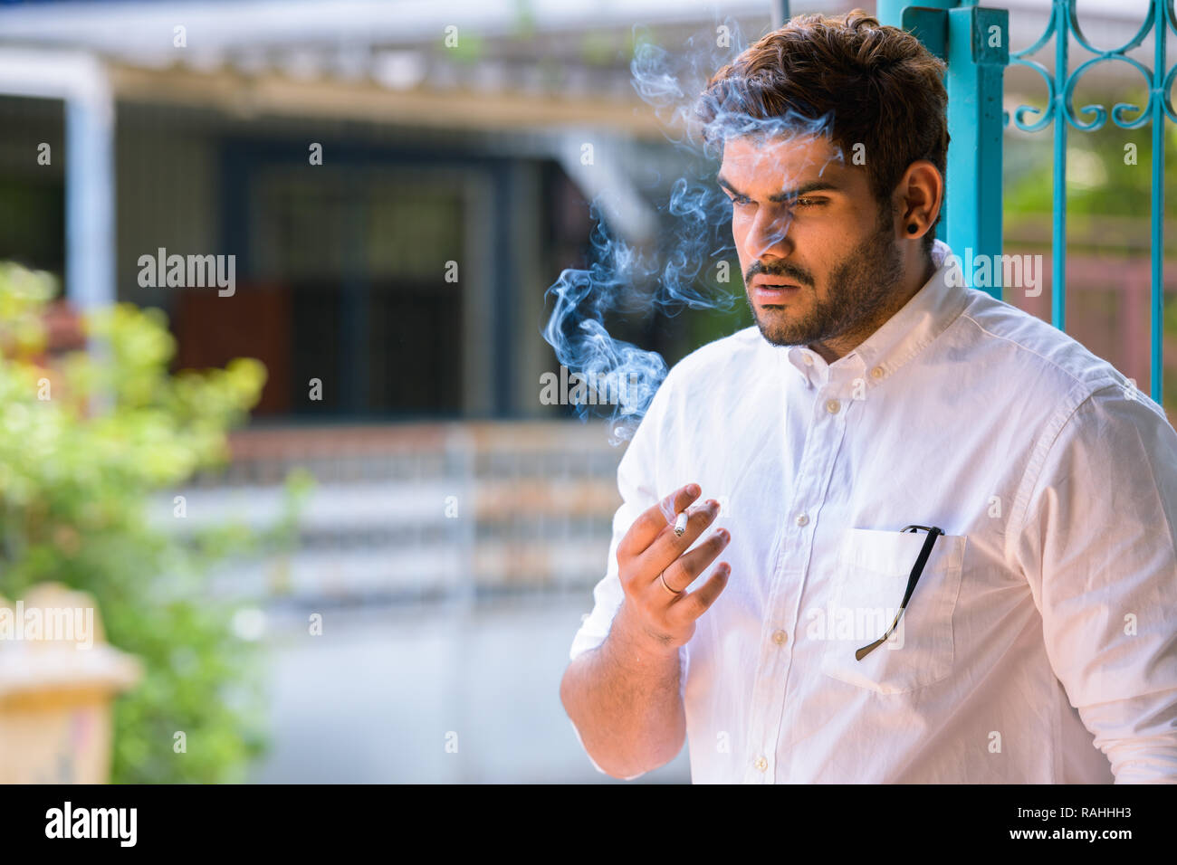 Les jeunes ont souligné l'homme Indien barbu pense en fumant à l'extérieur Banque D'Images