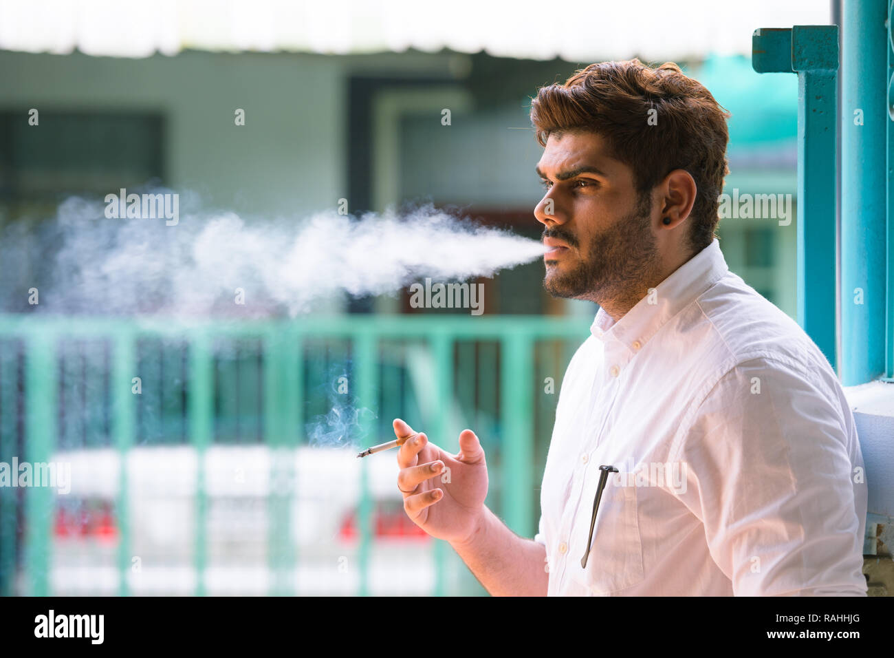 Voir le profil de jeune homme indien barbu beau fumeurs à l'extérieur Banque D'Images