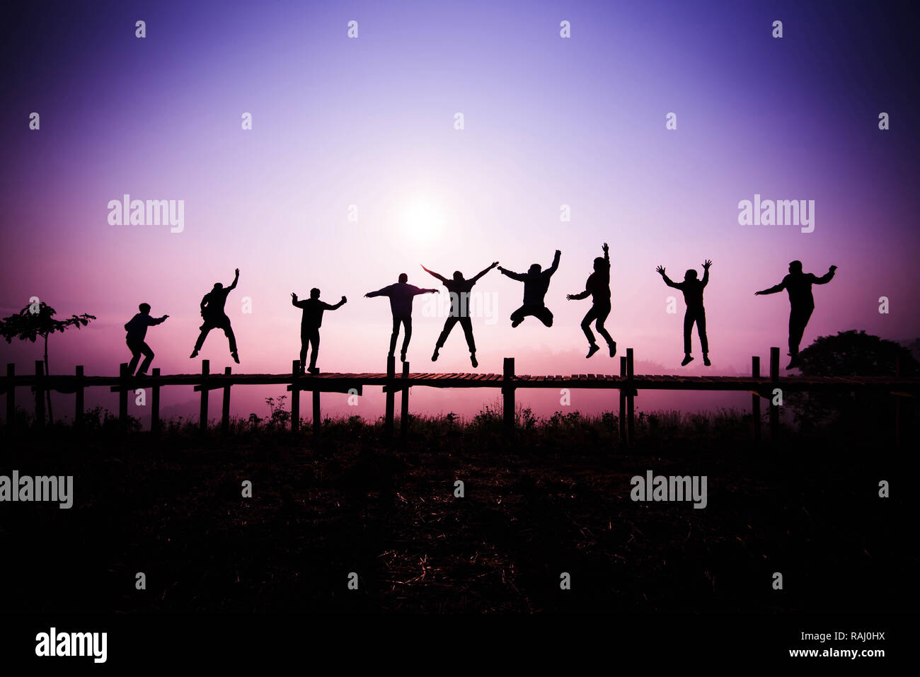 L'équipe de Jumping Silhouette / les amis de sauter sur le pont de bois sur la colline - profitez de joyeuse et amusante avec les gens de saut du lever ou du coucher du soleil dans la maison de vacances Banque D'Images